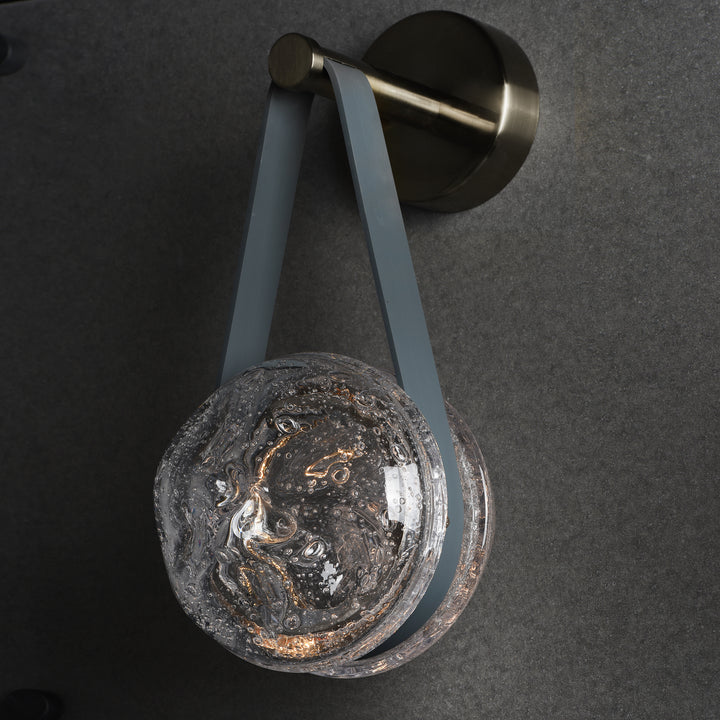 crater textured glass suspended wall lamp with leather strap creating warm ambient modern interior lighting