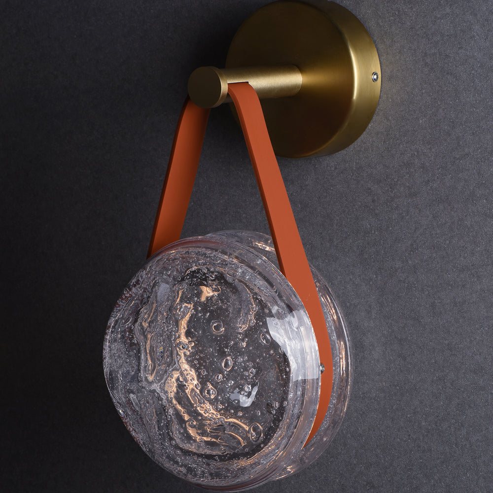 hanging crater glass wall lamp with leather strap used as modern bedside accent lighting