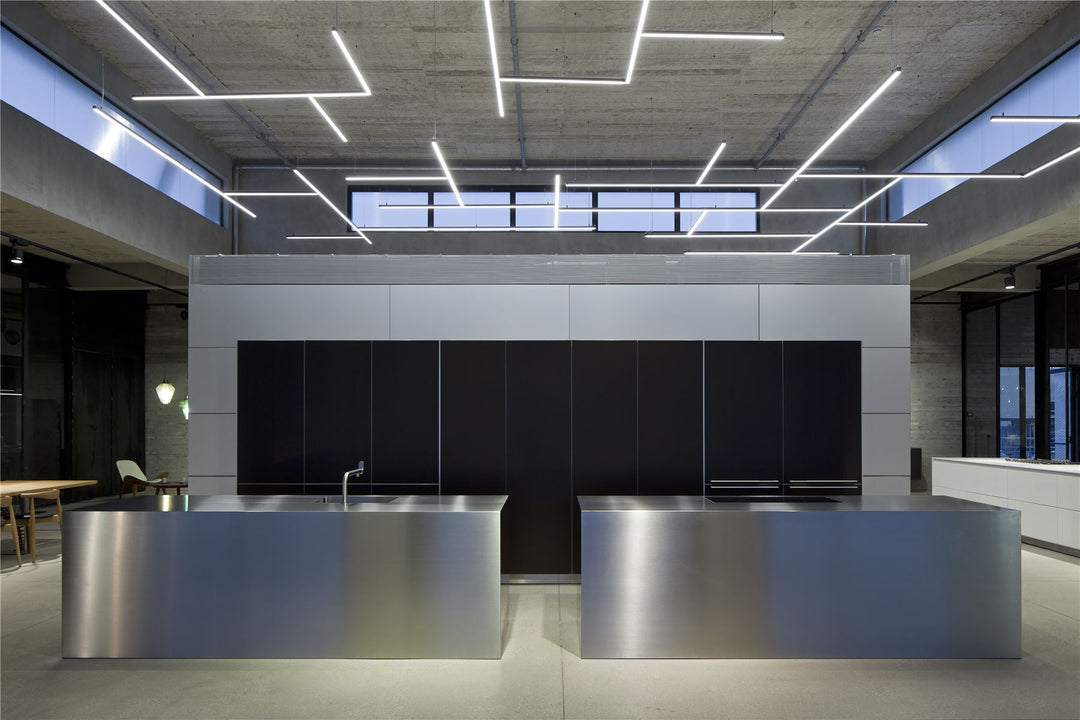 Lucretia custom linear lights in a modern industrial kitchen showroom featuring continuous architectural ceiling lighting.