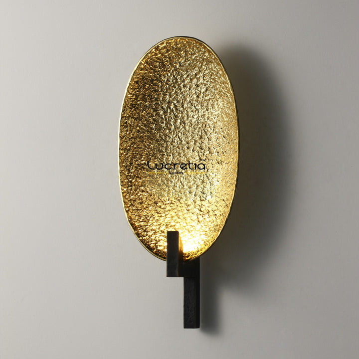 textured brass oval wall lamp installed on interior wall providing warm diffused ambient lighting ideal for hallways living rooms bedrooms and contemporary interior wall lighting