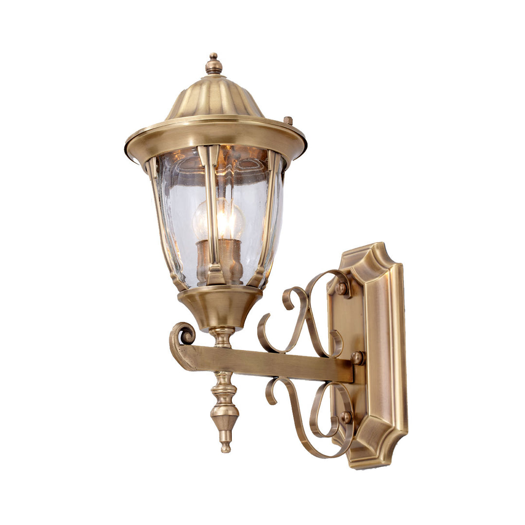 Brass outdoor wall lantern with clear glass and decorative arm.