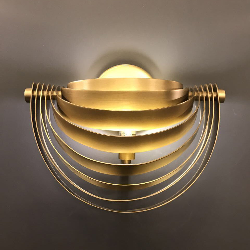 architectural brass wall lamp with layered semi circular design installed on interior wall ideal for ambient indoor wall lighting hallway wall light and contemporary home décor